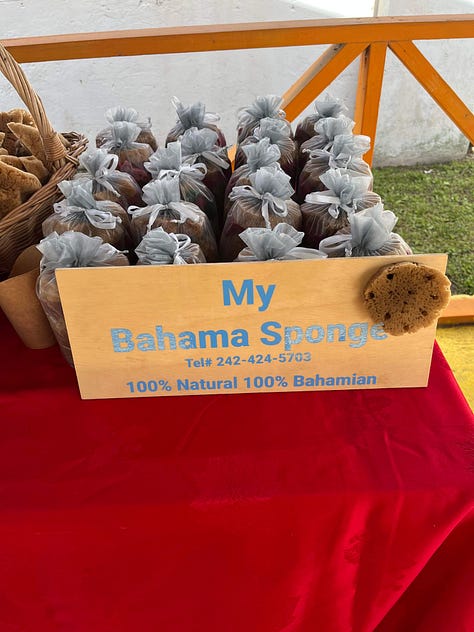 Left to right: Wodden tables with jars of homade body scrubs and lotions. Wodden Tables with homemade soaps. Table with a red table cloth featuring Bahama sponges