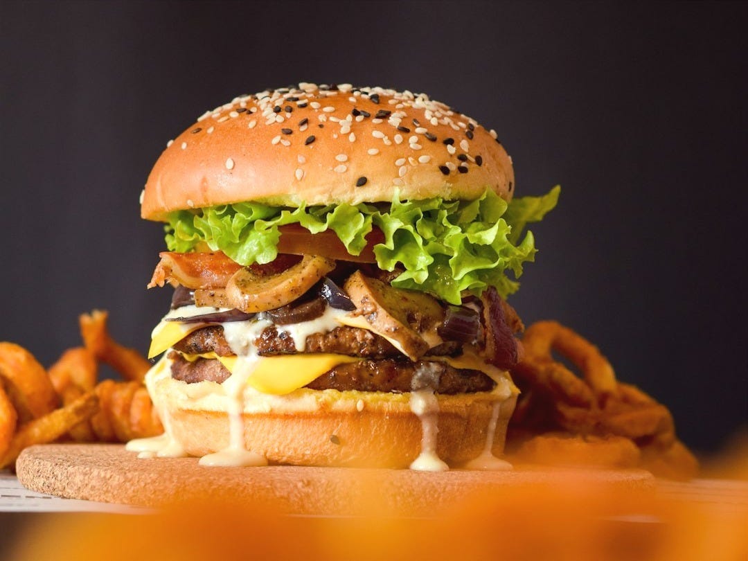 burger with lettuce and tomato on brown wooden tray