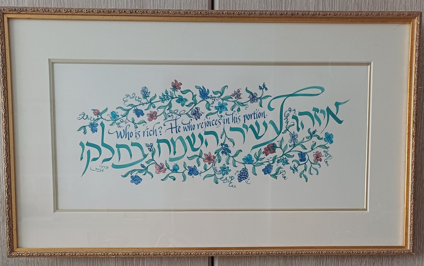 Calligraphy of the saying, Who is Rich? in Hebrew and English, surrounded by a garland of small blue, green, and purple flowers