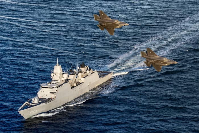Una nave olandese con numero di scafo F803 naviga nel Mar Baltico mentre due caccia olandesi F-35 sorvolano la zona.