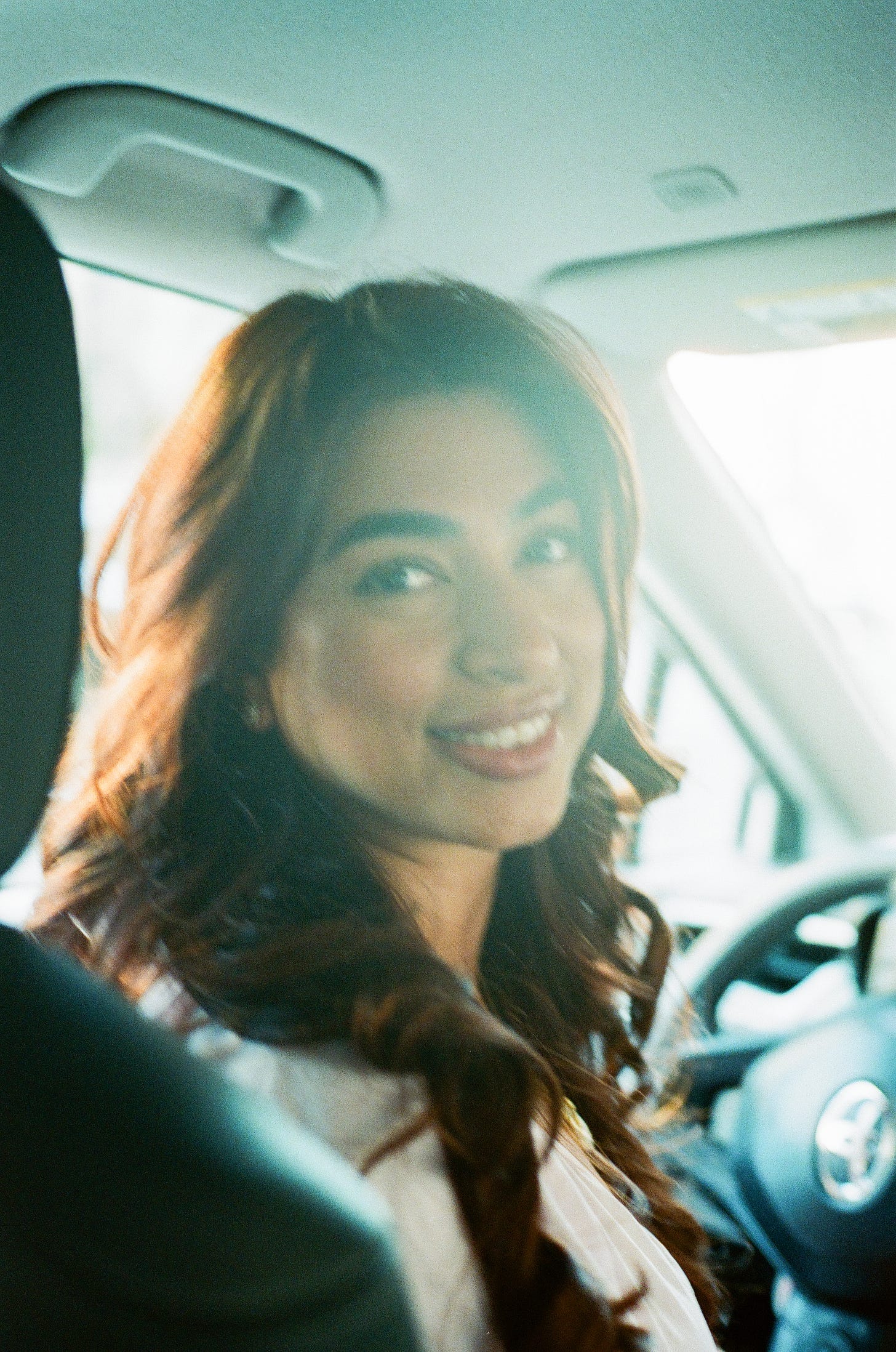 My lovely Lyft driver smiling bathed in light streaming through the windshield