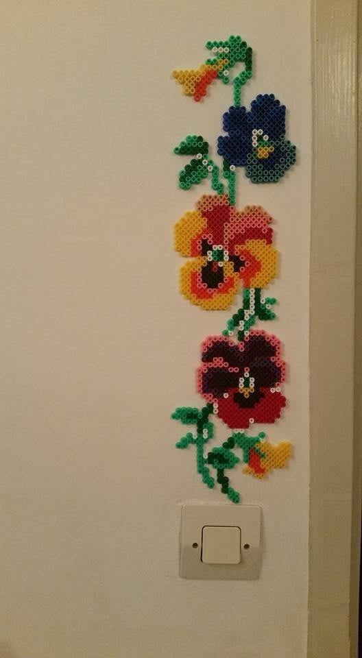 This may contain: a cross stitch flower design on the side of a white door with a light switch This may contain: a cross stitch flower design on the side of a white door with a light switch
