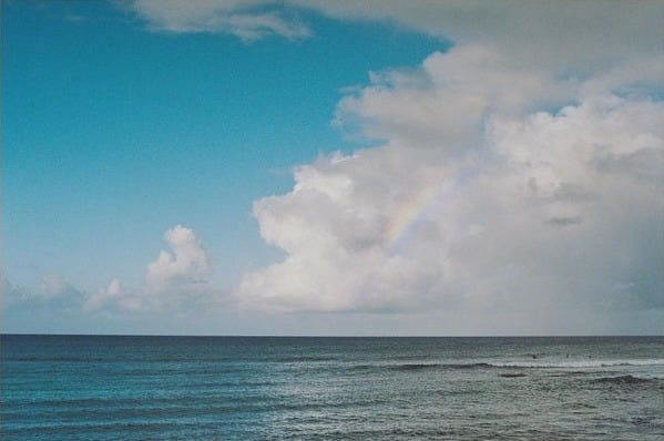 May include: A framed photograph of a blue ocean with white clouds and a faint rainbow in the sky.