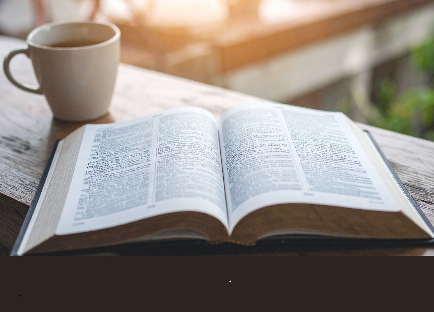 a Bible sitting on table with a cup of coffee