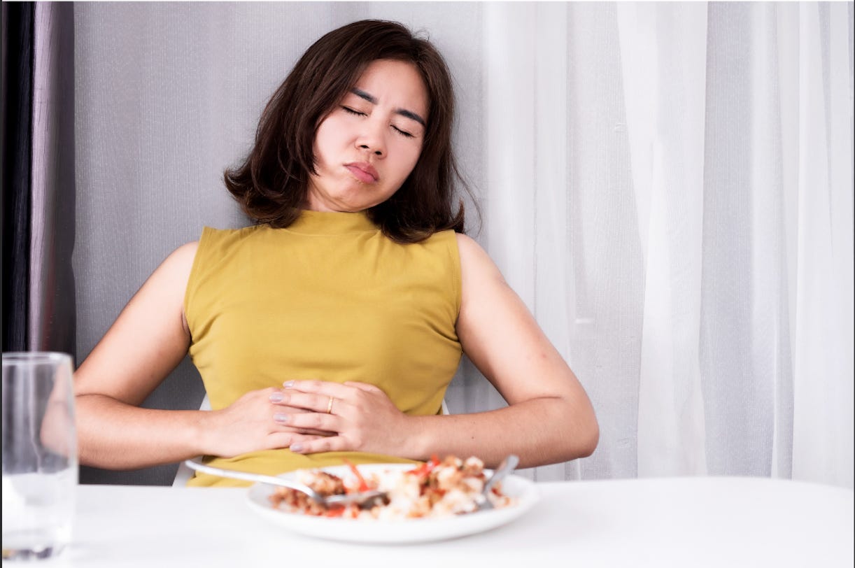 Girl struggling with bloating after a meal 