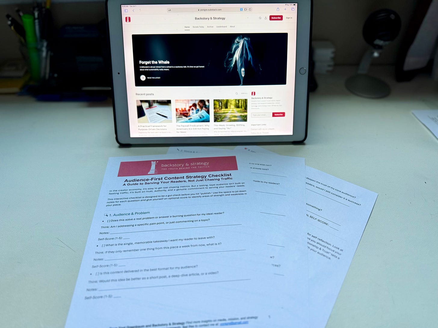 A photo of the printed 'Audience-First Content Strategy Checklist' laid out on a desk. In the background, an iPad displays the 'Backstory & Strategy' Substack homepage. A photo of the printed 'Audience-First Content Strategy Checklist' laid out on a desk. In the background, an iPad displays the 'Backstory & Strategy' Substack homepage.