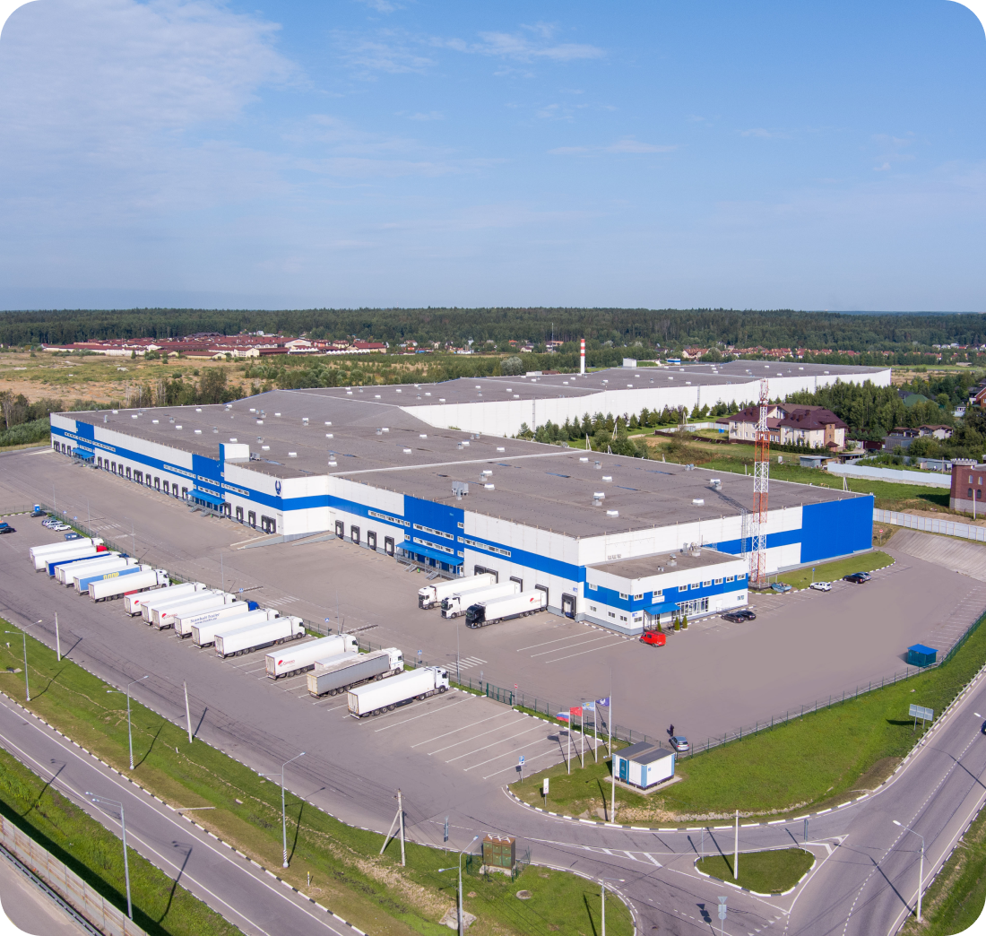 A large warehouse with many trucks parked in a parking lot

Description automatically generated