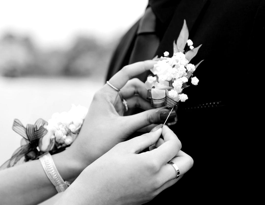 woman putting white flower on man's suit