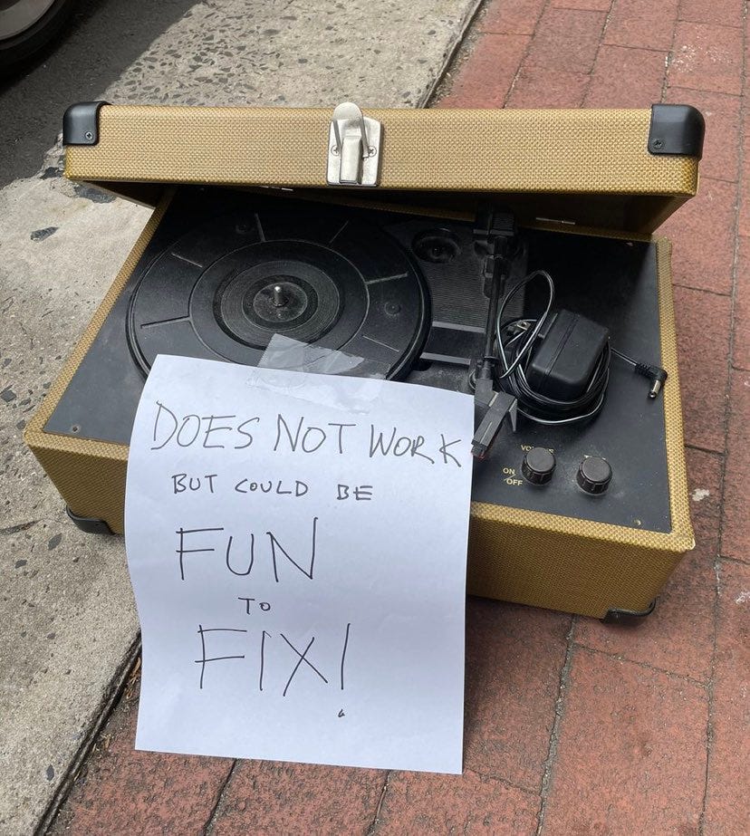 Broken record player with sign that says "does not work but could be fun to fix!" Broken record player with sign that says "does not work but could be fun to fix!"