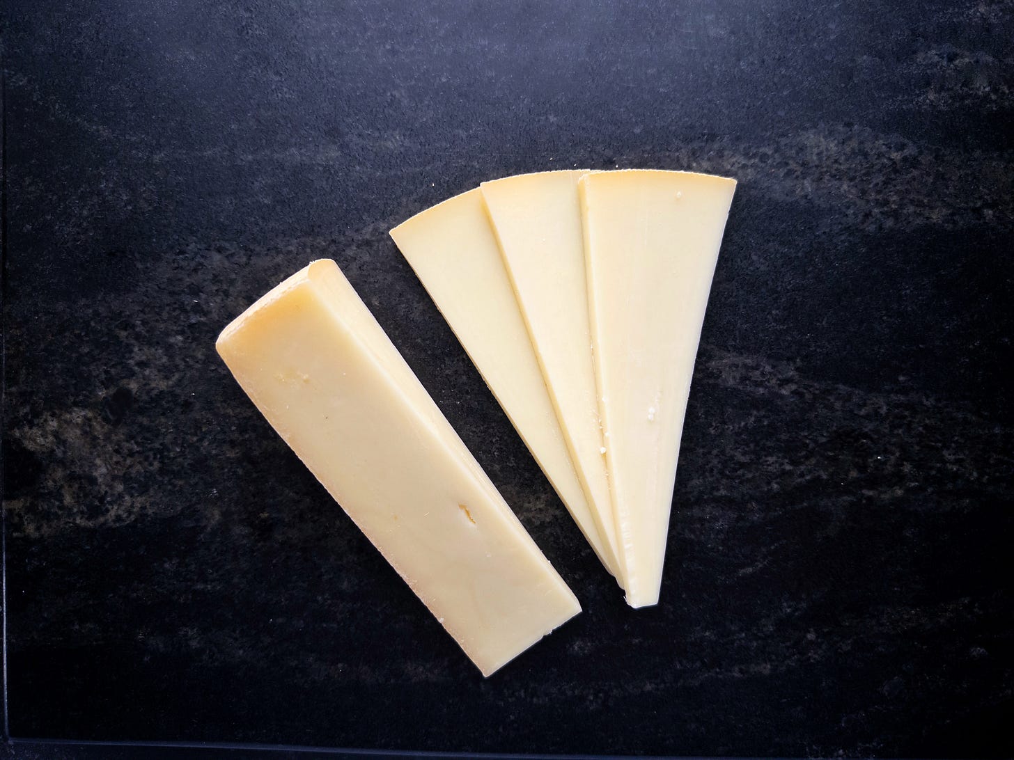A wedge of Raclette, sliced thinly