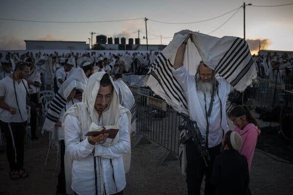 A crowd of Jewish worshipers praying outdoors.