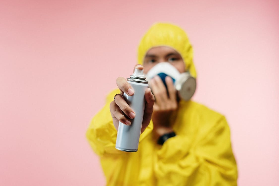 Man in Coveralls Holding Spray Bottle