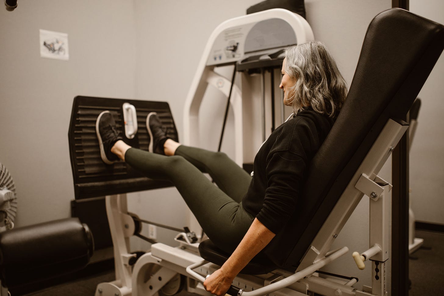 Gray-haired woman on a leg press in a gym Gray-haired woman on a leg press in a gym