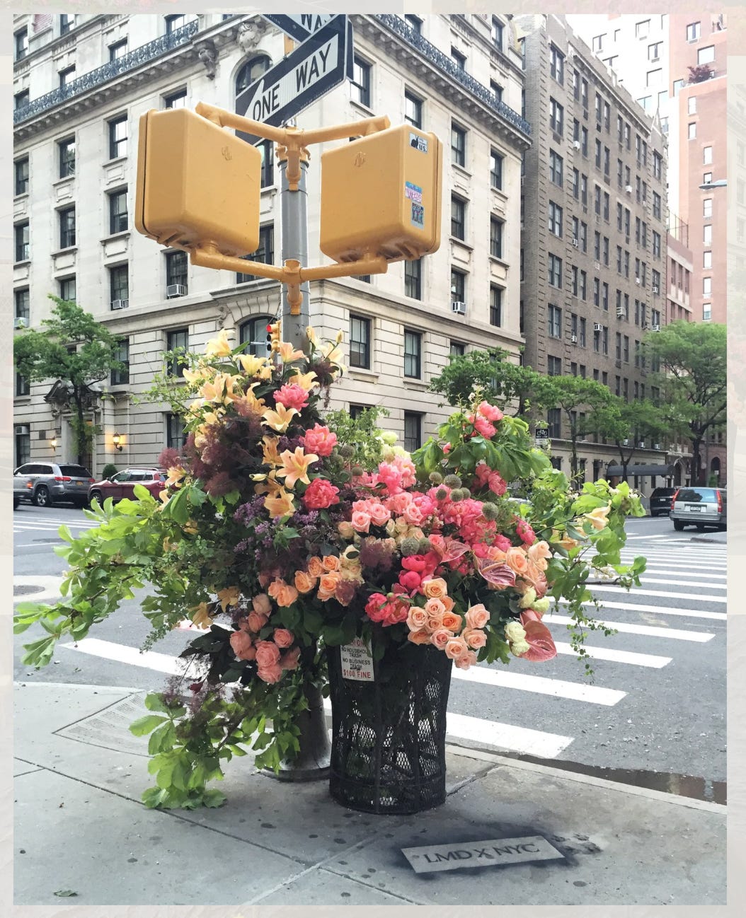 Color photo of a trash can bursting with an extravagant floral arrangement on a New York City corner.