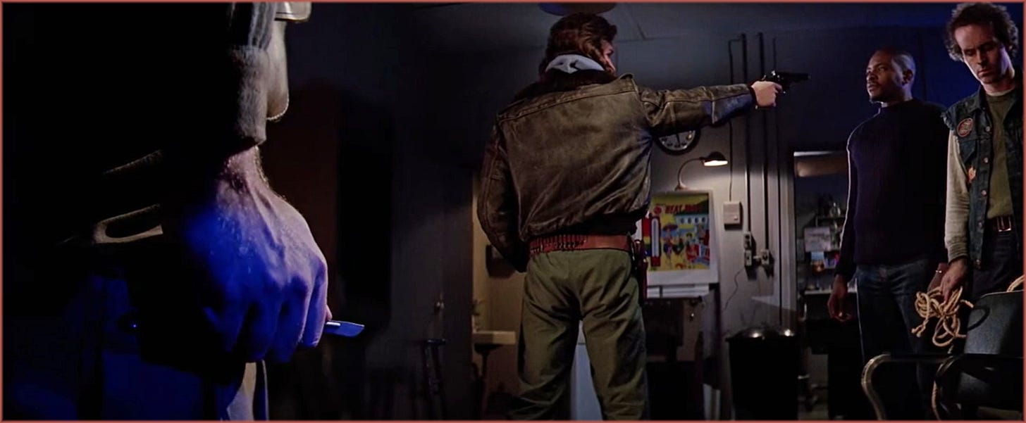 Wide interior shot from The Thing (1982): Clark's hand holding a scalpel in extreme foreground on the left, MacReady pointing a gun at Childs in the midground center, Childs and Palmer holding rope standing sharp in the background right. A split diopter lens keeps all planes simultaneously in focus.
