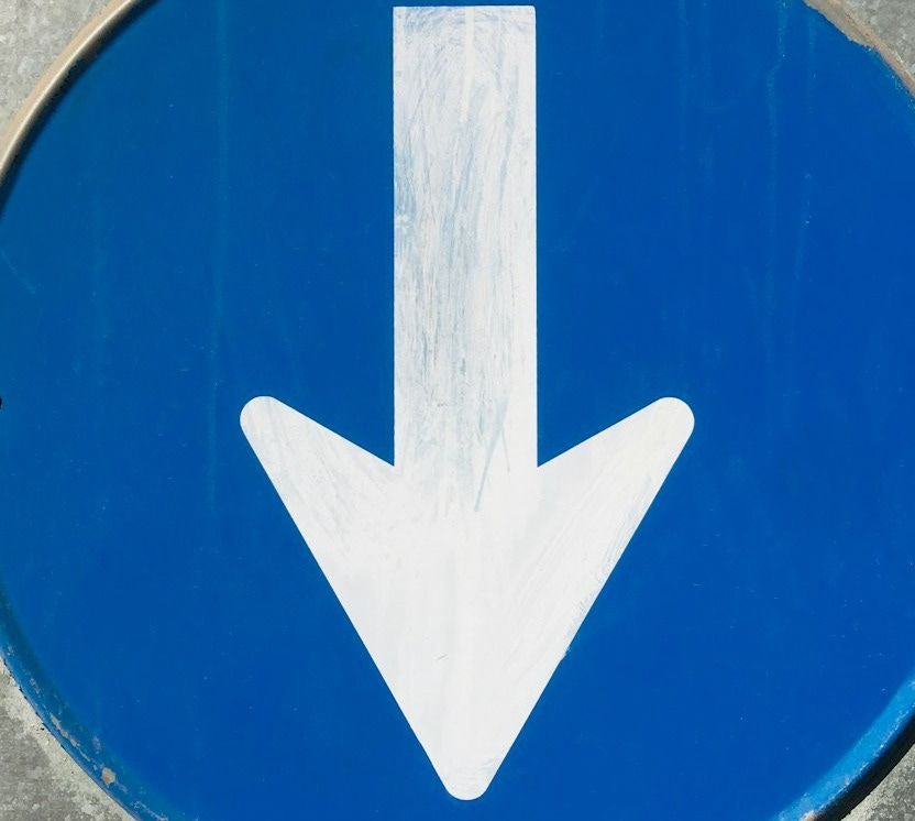 a close up of a blue sign with a white arrow a close up of a blue sign with a white arrow