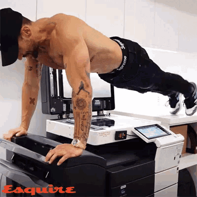 a shirtless man is doing push ups in front of a printer that says esquire on it a shirtless man is doing push ups in front of a printer that says esquire on it