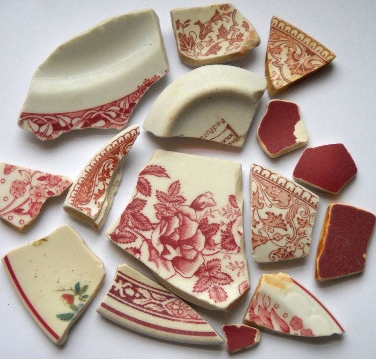 This may contain: several pieces of pottery sitting on top of a white tablecloth covered surface with red and white designs