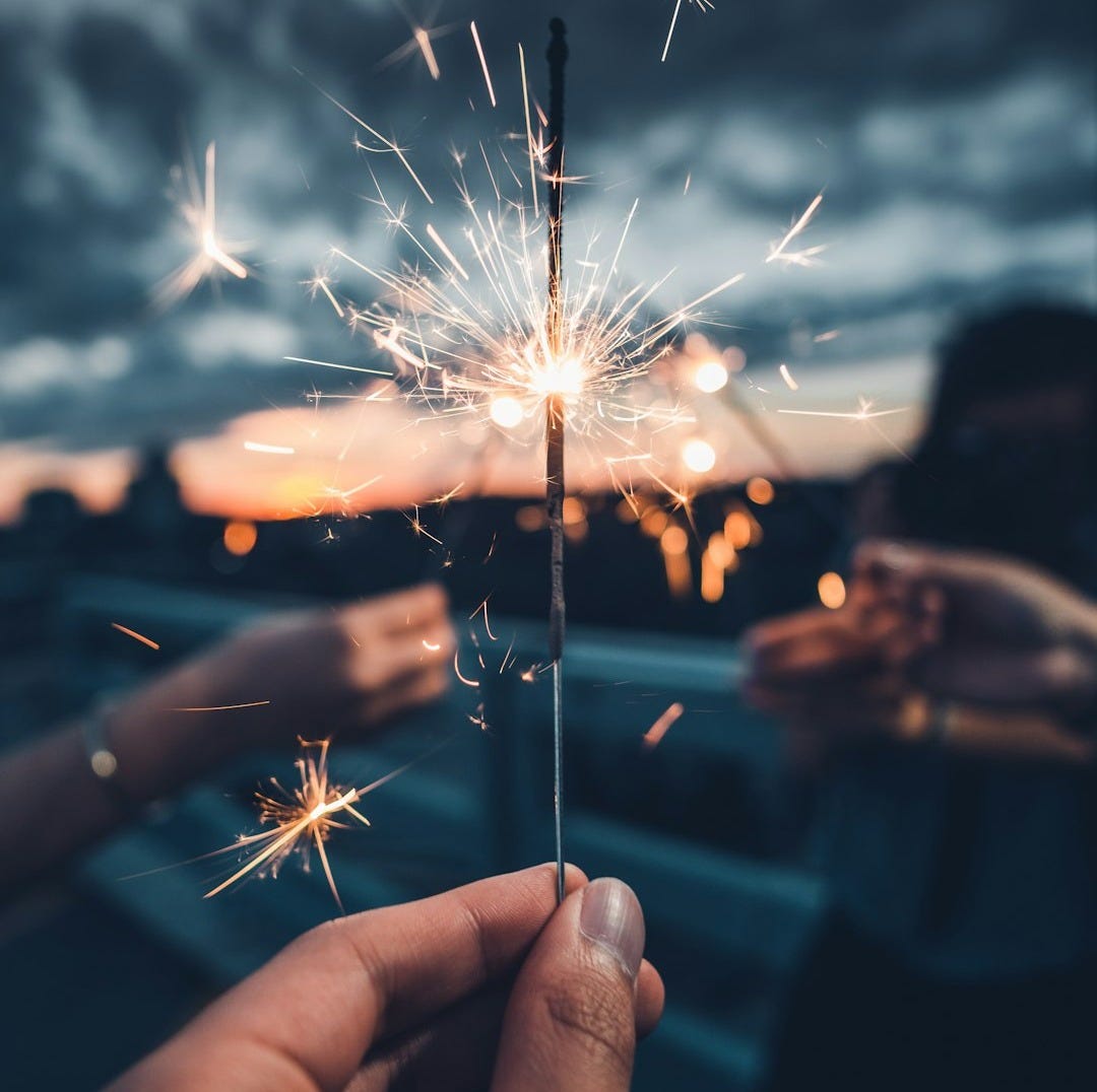 photo of person holding lighted sparkler