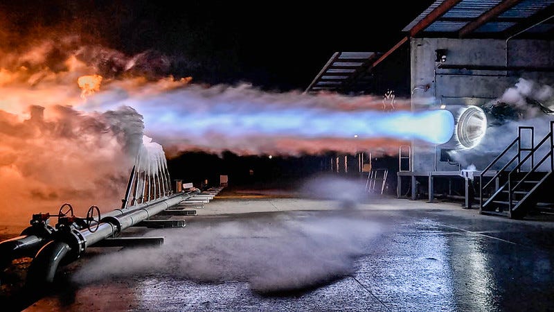 a rocket engine horizontally firing blue exhaust on a test stand