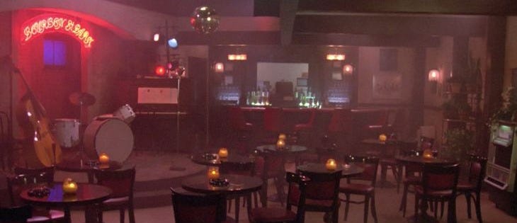 This may contain: an empty restaurant with tables and chairs in the middle is lit up by red lights