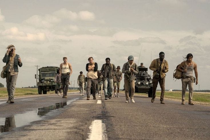 This may contain: a group of people walking down the road with an army vehicle in the back ground