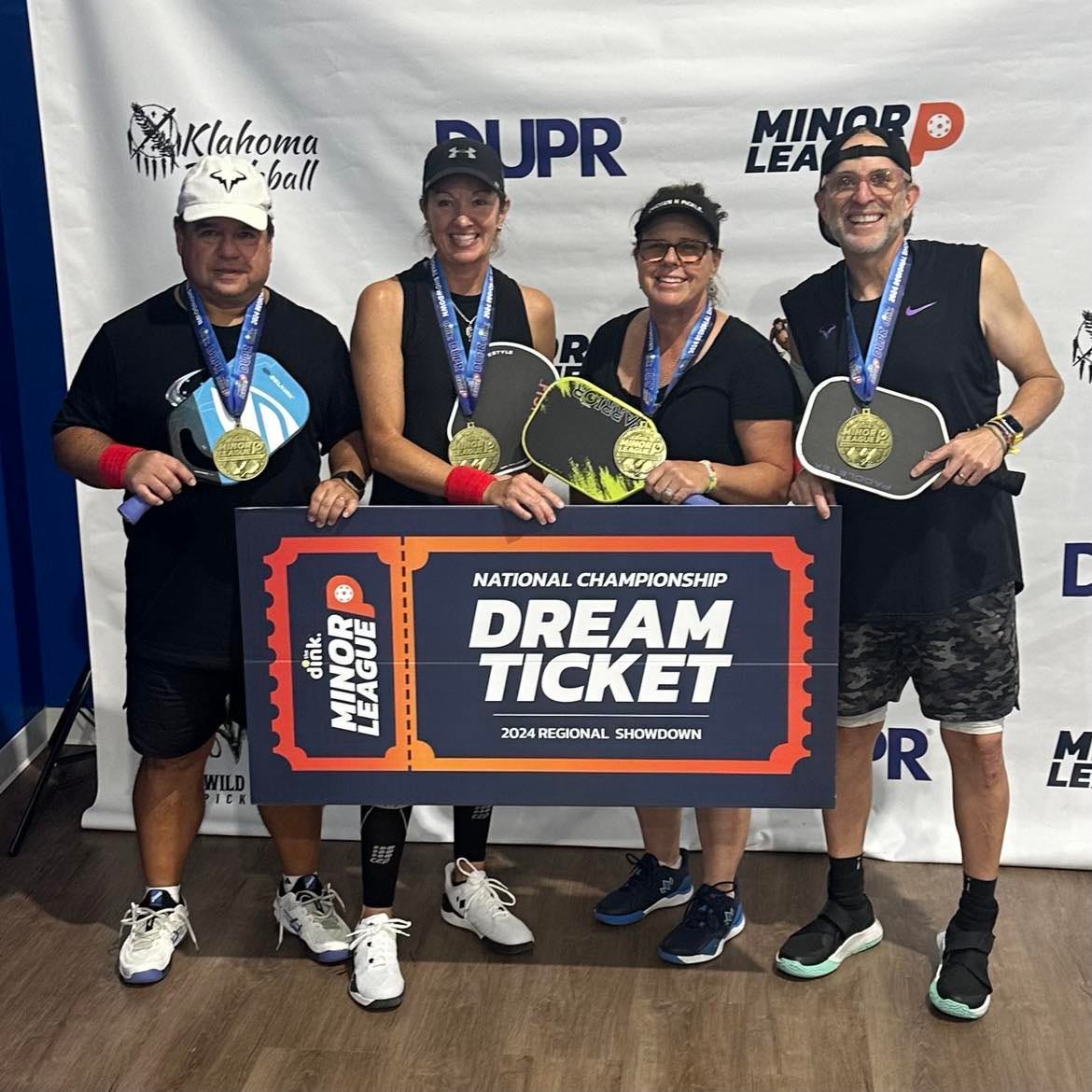 Four pickleball players holding rackets and wearing gold medals