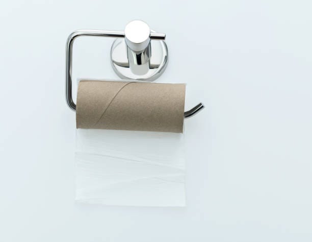 Empty toilet paper roll handing on white background stock photo Empty toilet paper roll handing on white background stock photo