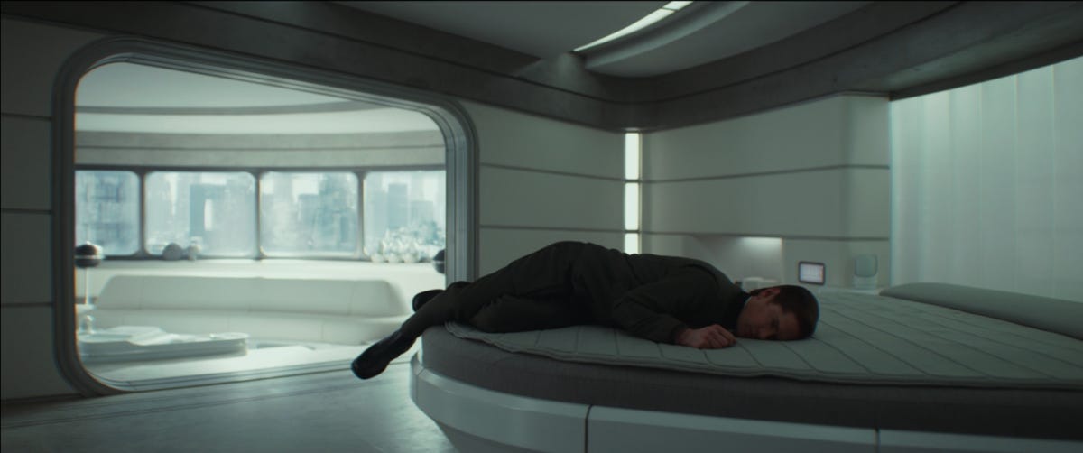 image of the character Syril Karn awkwardly lying on a bed with his legs dangling off the side because he is very sad.