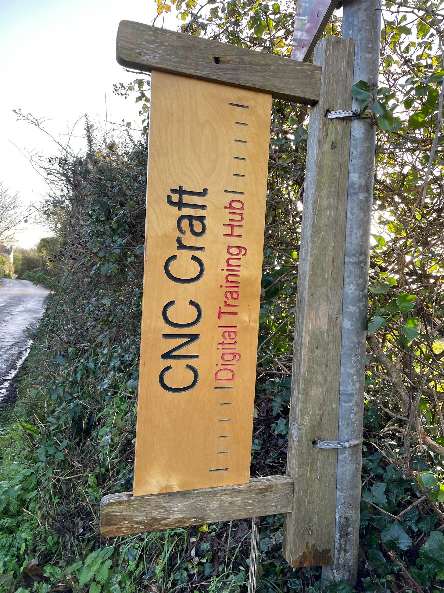 A sign hangs on the side of the road that reads CNC Craft Digital Training Hub