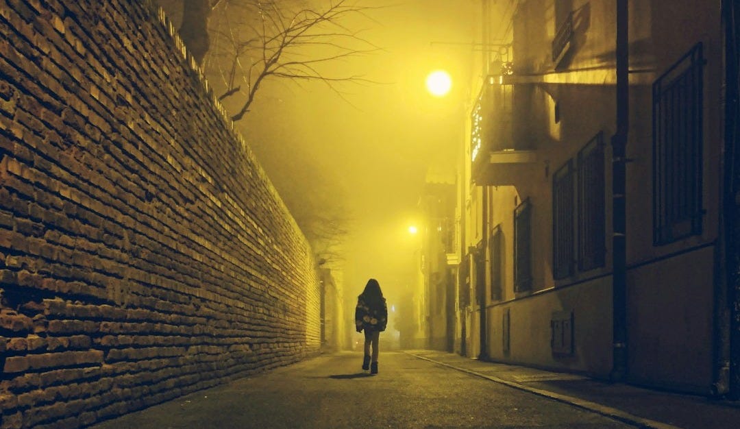 a person walking down a street at night a person walking down a street at night