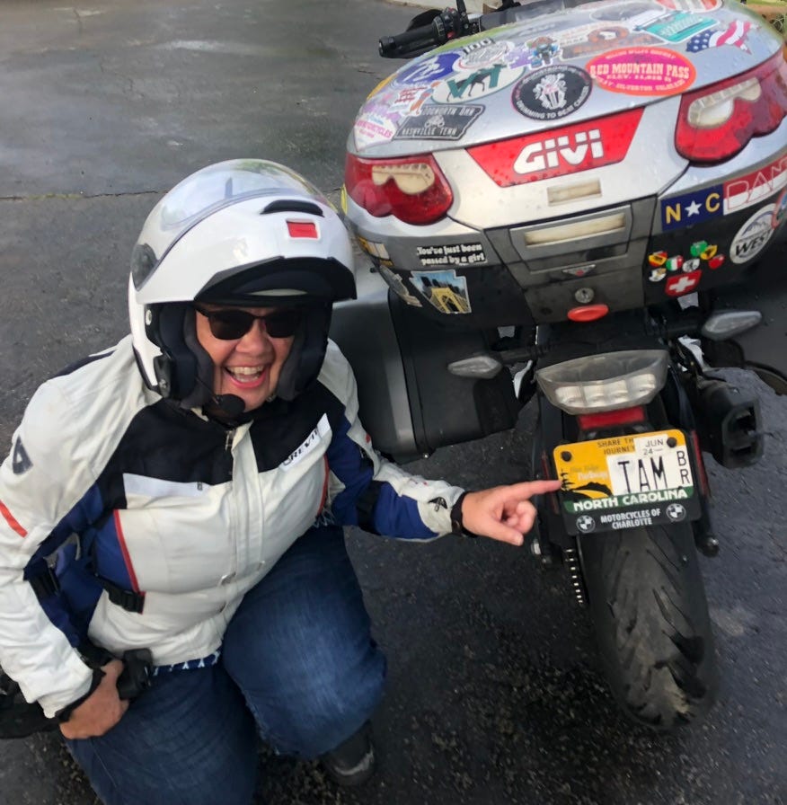 woman in motorcycle gear with motorcycle