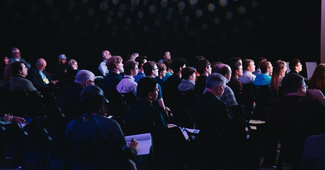 crowd of people sitting on chairs inside room crowd of people sitting on chairs inside room