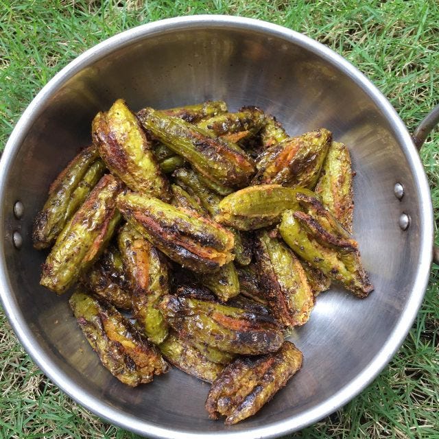 A aluminum vessel placed on grass with stuffed tinda/dondakaya inside. A aluminum vessel placed on grass with stuffed tinda/dondakaya inside.