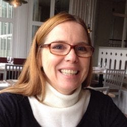 A imagem contém uma mulher com cabelo loiro, ela usa óculos