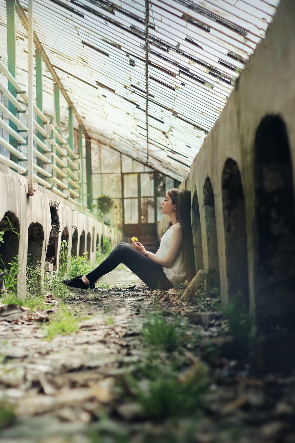 woman sitting between concrete fence at daytime woman sitting between concrete fence at daytime
