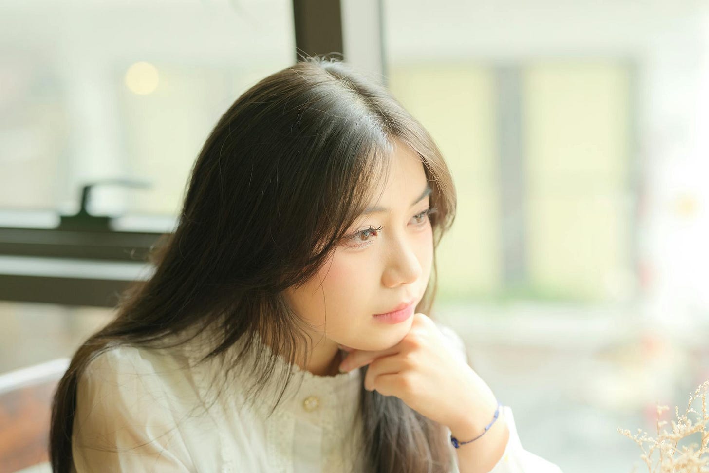 Young woman looking out the window while questioning kindness or people pleasing Young woman looking out the window while questioning kindness or people pleasing