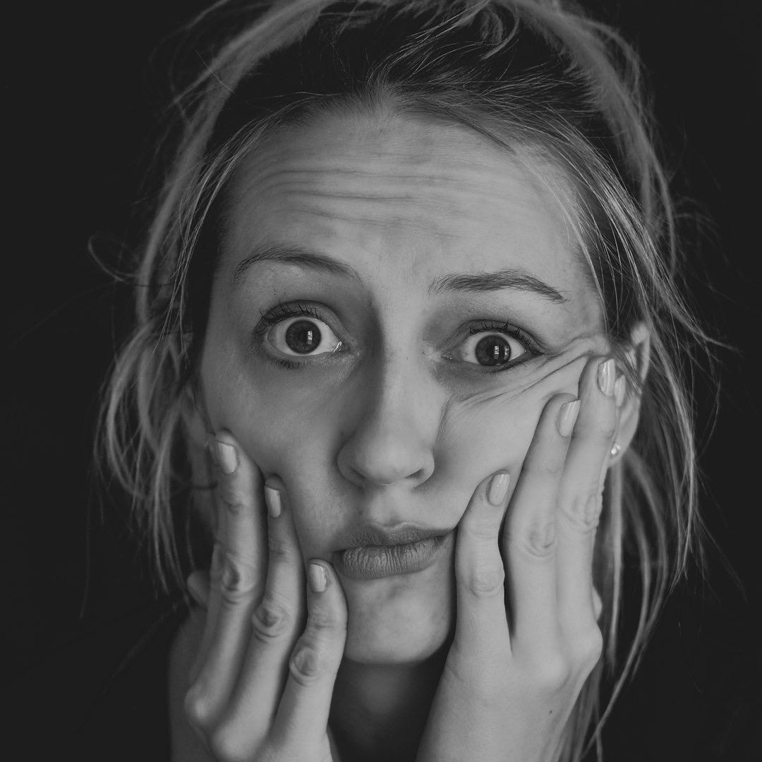 grayscale photo of woman covering her face with her hand