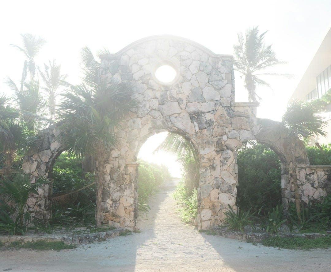 Jesus' Heavenly Welcome: A Stone Gate with Palm Trees in the Background and Foggy