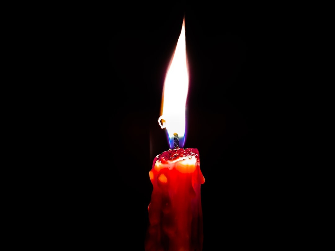 a red candle with a lit candle stick sticking out of it