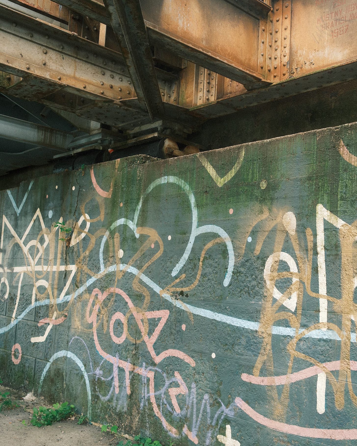 vertical photograph under a rusted rail bridge, with graffiti vertical photograph under a rusted rail bridge, with graffiti