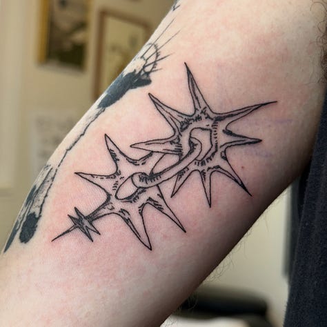 9 photos of tattoos i did this month. from top left to bottom right: a stuffed animal from item label called a peepy, a spiky chain link, a dog dragon, a starry sacred heart, a little guy holding a leaf, another chainlink with a dark black spiky background, another chain link, a brick with leaves growing out of it, and a spiral star on someones elbow (ouch!)