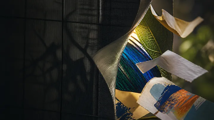 Torn fabric exposes a colorful ball, paint swatches, and a green leaf on a textured surface.