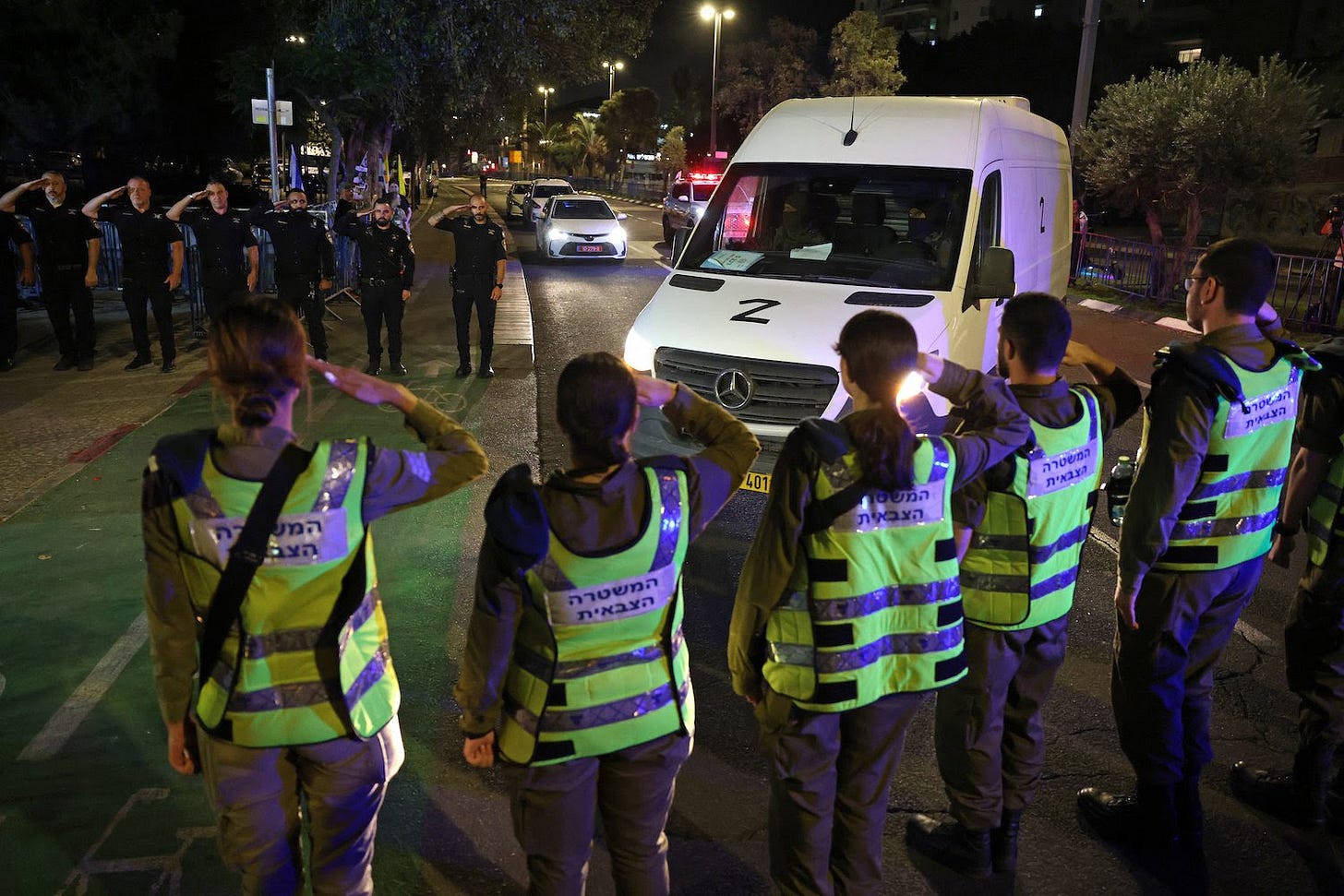 Israelis in Tel Aviv salute at vehicles transporting the bodies of four hostages handed over following a cease-fire deal between Israel and Hamas.