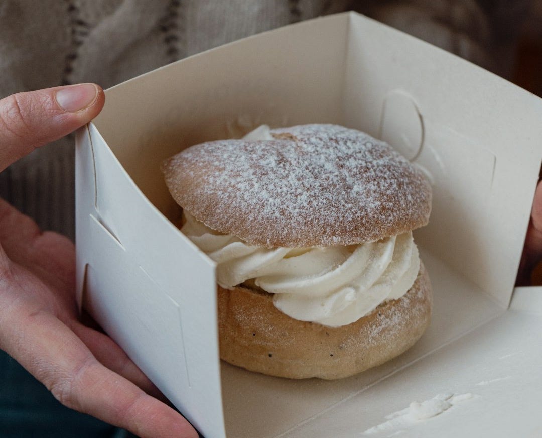 a person holding a box with a pastry inside of it a person holding a box with a pastry inside of it
