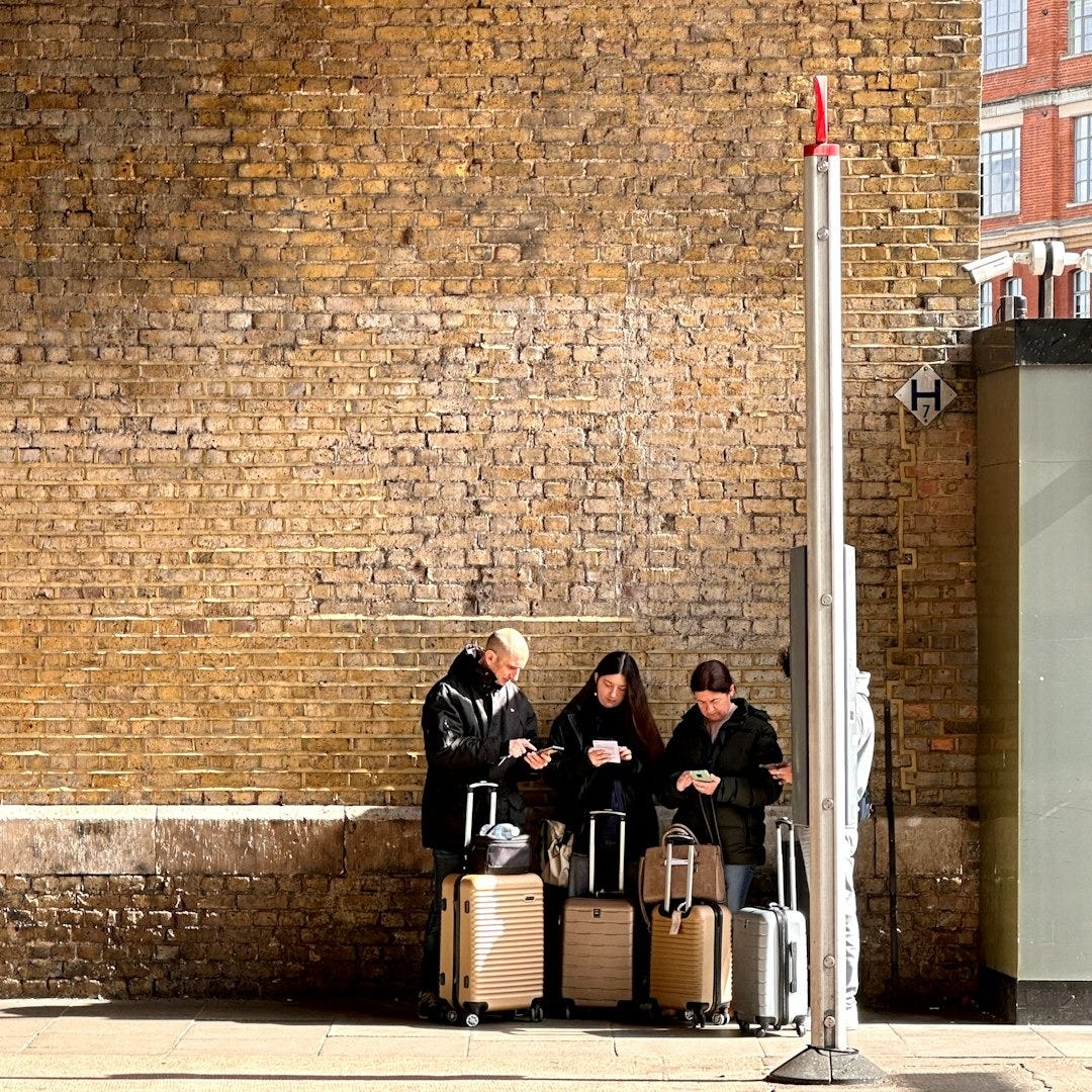 A group of people sitting on a bench next to luggage