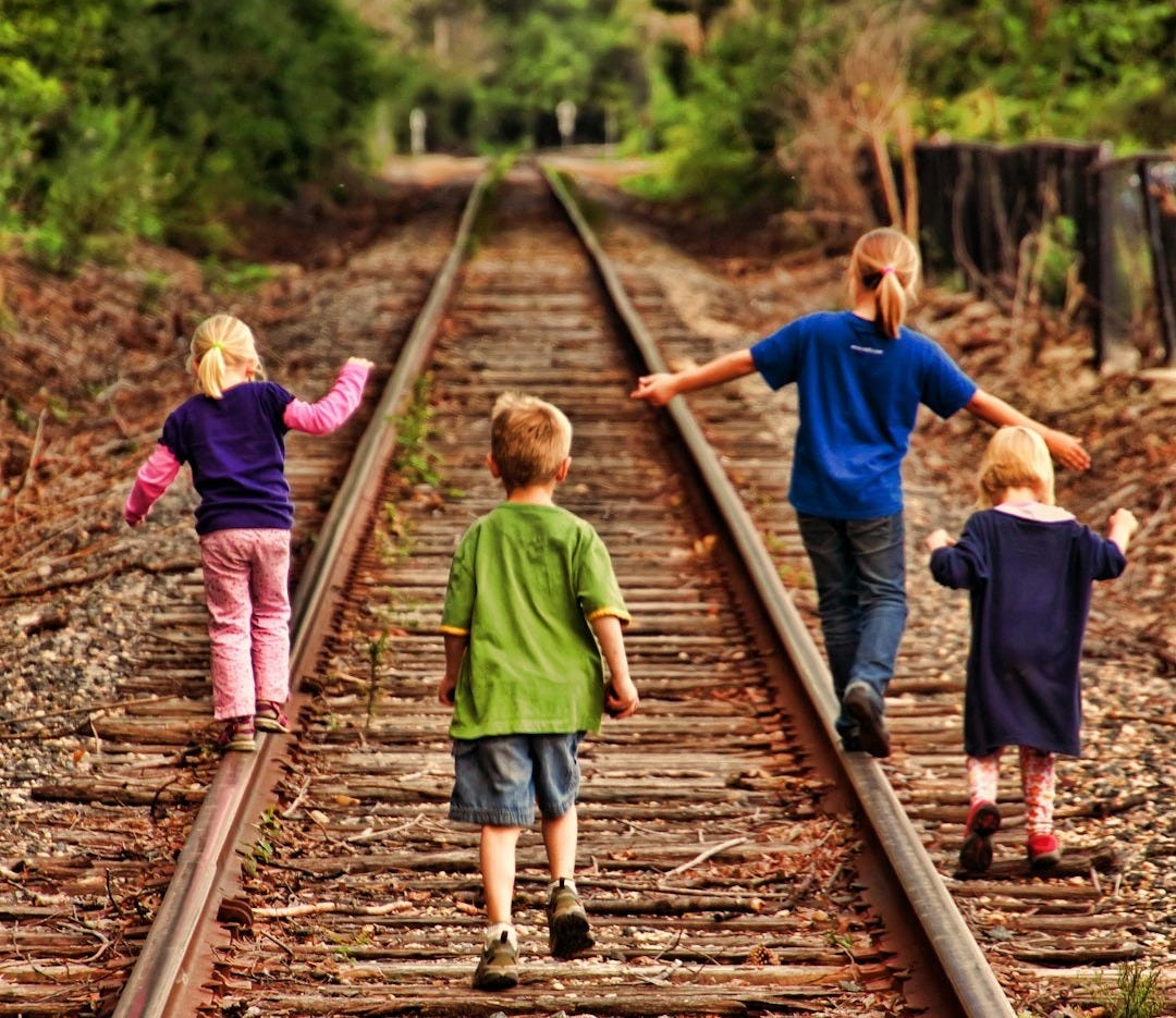 Four children walk down railroad tracks