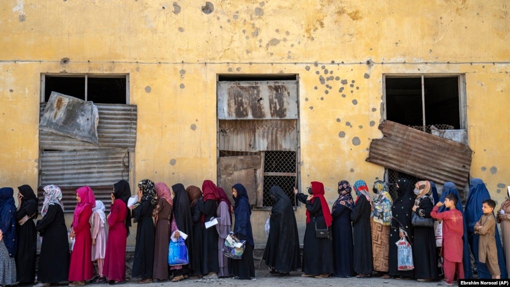 Afghan women wait to receive food rations distributed by a humanitarian aid group in Kabul.
