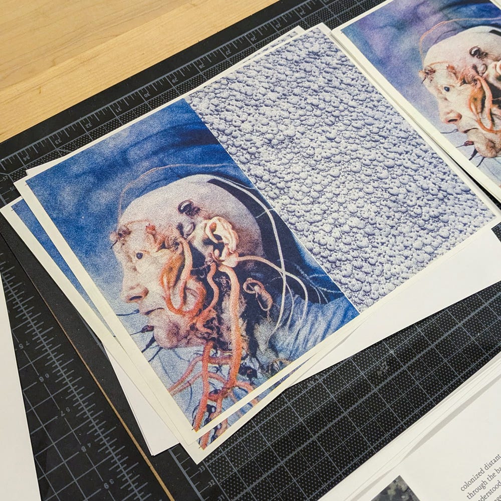 A close-up photograph of Risograph-printed artwork featuring a surreal illustration of a human head with organic and mechanical elements intertwined, resembling wires and tentacle-like structures emerging from the skin. The left side of the image shows the detailed portrait, while the right side contains a textured pattern of repeating small faces. The prints are stacked on a black cutting mat with measurement markings, placed on a wooden surface.