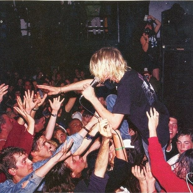 This may contain: a crowd of people reaching up to touch a man on his shoulders